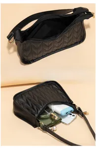 Spacious interior of a black quilted shoulder bag holding a smartphone and wallet