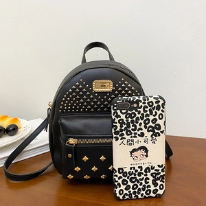 Mini black backpack with gold pyramid studs and metallic plate, shown with a phone case