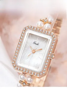 Macro shot of square rose gold watch with mother of pearl dial and pearl strap