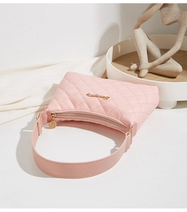 Close-up of pink quilted underarm bag with gold metal logo and silk texture background