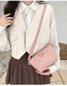Close-up of pink crossbody bag with geometric pattern worn by model in elegant outfit
