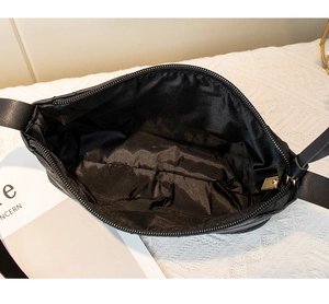Close-up of the black quilted crossbody bag opening showing main compartment and zipper