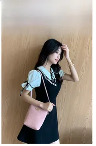 Pink minimalist bucket bag with textured weave and gold logo on a model