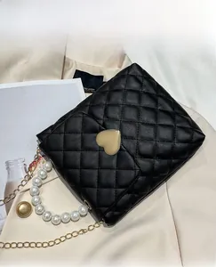 Détail du mini sac matelassé noir avec fermoir cœur et bandoulière en perles