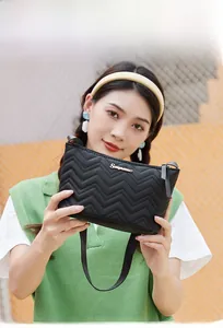 Close-up of black wave quilted pattern shoulder bag with golden metal logo detail