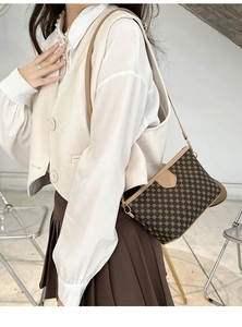 Model wearing a vintage brown crossbody bag with gold chain patterns and slim strap