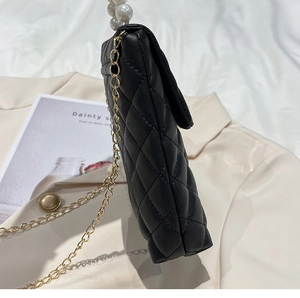 Détail du sac à téléphone matelassé noir avec bandoulière dorée et décor de perles