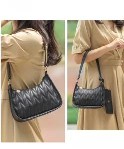Detailed close-up of a black quilted shoulder bag with V-shaped stitching and gold zipper