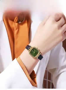 Close-up of vintage square watch with green dial and black leather bamboo strap