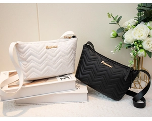 Detailed view of quilted wave pattern leather bags in white and black with gold logo