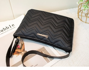 Detail of black zigzag quilted leather bag featuring gold metallic logo and sleek texture
