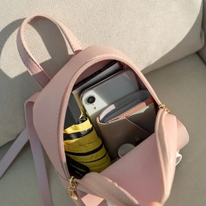 Mini sac à dos en cuir rose pour filles montrant le rangement interne et accessoires