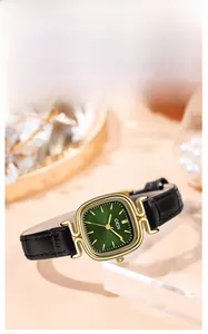 Detail shot of vintage square green dial watch with gold case and black leather strap