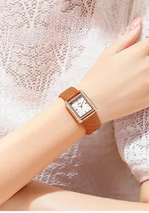 Detail of rectangular rose gold watch with diamond bezel and brown quilted leather strap