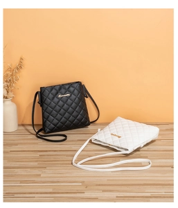 Close-up of quilted leather crossbody bags with golden S-logo in black and white colors