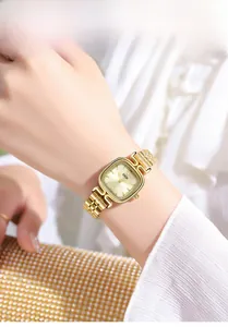 Detail of elegant gold square watch featuring a vintage metal chain strap on wrist