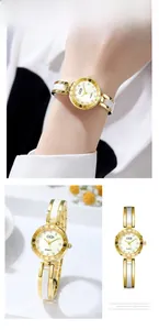 Close-up of elegant gold watch with white inlay band and sparkling rhinestone indices