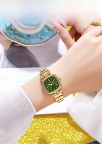 Close-up of vintage square emerald watch with golden steel strap worn on wrist
