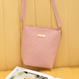 Minimalist pink woven texture bucket handbag with gold hardware displayed on warm background