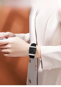 Minimalist square quartz watch with black dial and silver case on a woman's wrist