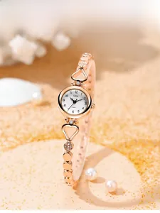 Detail of rose gold Gedi quartz watch with crystal heart bracelet on sand and pearls
