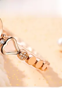 Detail of rose gold heart-shaped bracelet watch with crystals on a pearly background