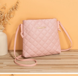 Detail of pink quilted crossbody bag featuring a golden logo and elegant leather texture