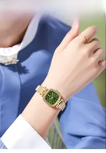 Close-up of a ladies' square gold watch with green sunray dial and mesh strap on wrist