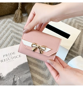 Détail du portefeuille en cuir rose avec rabat blanc et petit nœud doré élégant