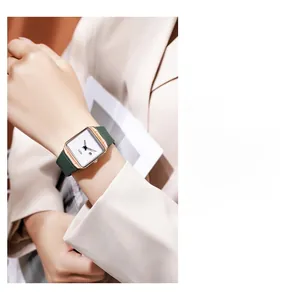 Detail of square quartz watch with rose gold case and green strap worn on wrist