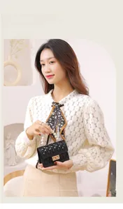 Detail of black quilted mini bag featuring pearl handle, gold lock and floral scarf accent