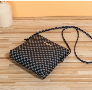 Close-up of black crossbody bag with grey geometric patterns and gold metal logo