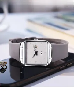 Macro detail of square silver watch case with grey silicone strap and date window