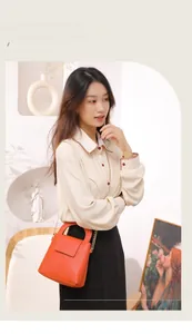 Sac à main chic en cuir orange avec chaîne porté avec une blouse vintage brodée