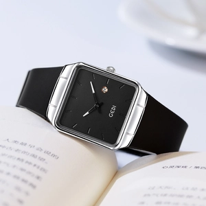 Minimalist square quartz watch with black dial and date window on open book