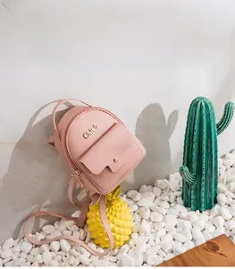 Detail view of mini light pink backpack featuring pebble grain texture and metal logo