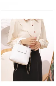 Détail d'un mini sac Boston blanc avec chaîne dorée et poignée porté par un modèle