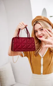 Close-up of wine red quilted mini handbag featuring gold chain strap and top handle detail