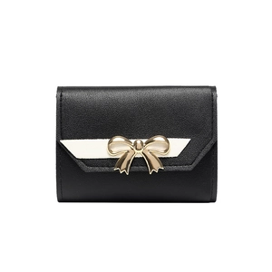 Women's small tri-fold wallet in black pebbled leather with a gold bow accent