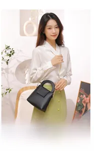 Détail d'un sac à main en cuir noir avec bandoulière dorée dans un cadre de vie urbain