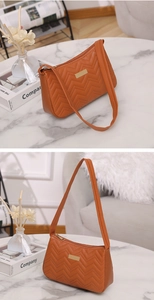 Detail of caramel faux leather bag with V-shaped quilting and gold metal accent