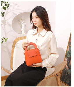 Sac à main chic en cuir orange tenu par un mannequin sur une chaise de créateur