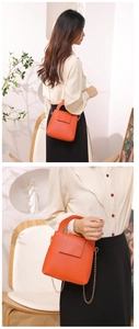 Détail du mini sac Boston en cuir grainé orange avec bandoulière chaîne dorée