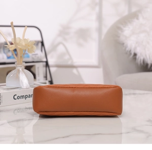 Detail view of the brown quilted leather handbag base with fine stitching on marble