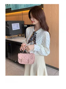 Pink quilted crossbody bag with gold buckles displayed in a cozy cafe setting