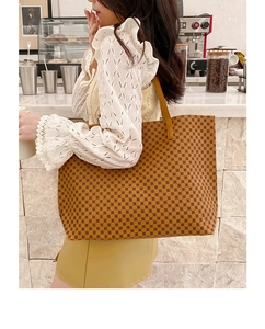 Brown tote bag with circle print shown on model in a cozy cafe setting