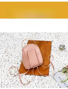 Pink mini faux leather backpack back view with adjustable straps on a rustic wood surface