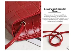 Close-up of red crocodile embossed leather bag with detachable strap and metal eyelets