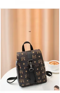 Detail of vintage monogram backpack with leather straps and metal buckle on a desk