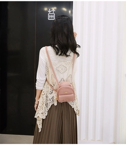 Rear view of a pink leather mini backpack worn by a model in a modern interior